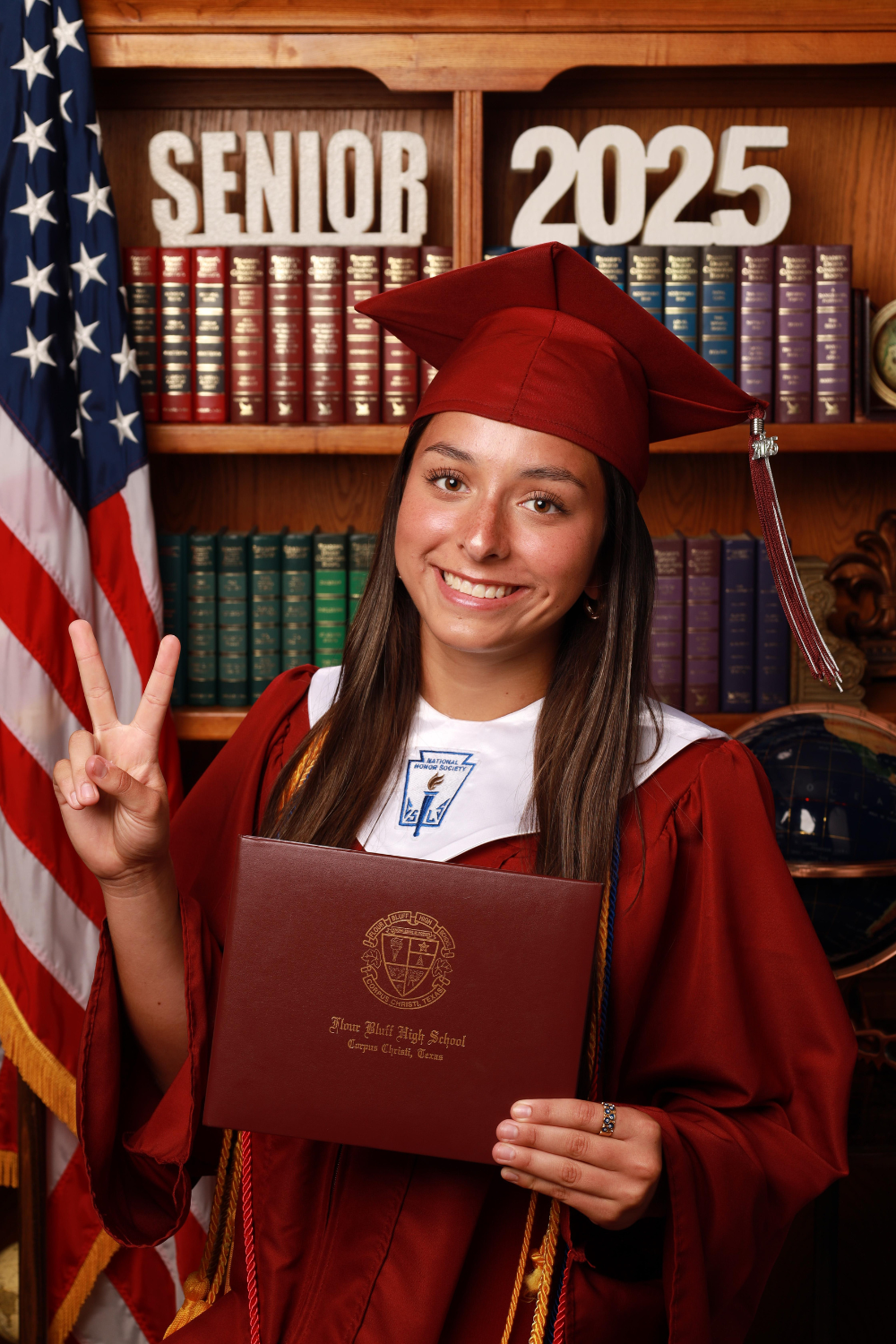 Female graduate wearing a red graduation cap and gown holding a diploma.