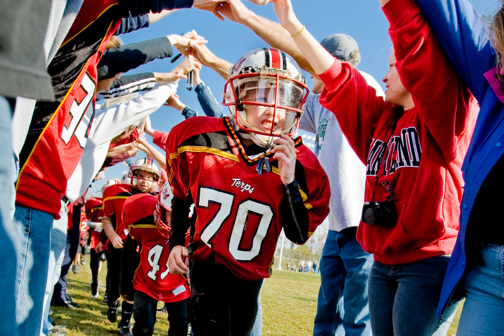 youth football player running through a cheer tunnel